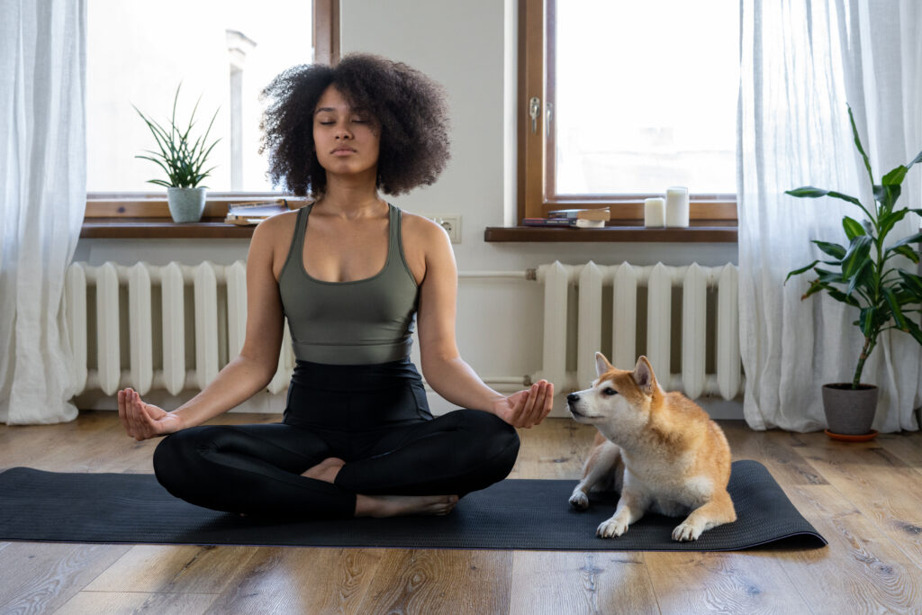 Woman doing yoga beside her dog